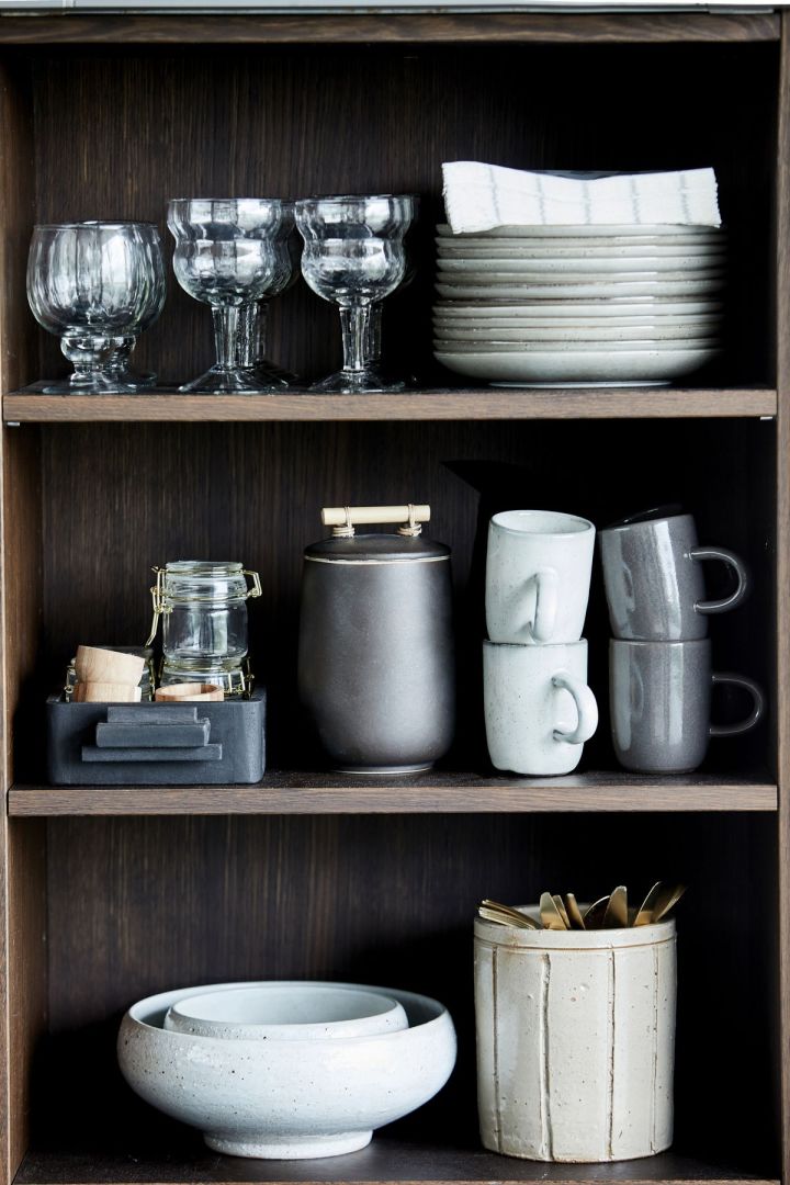 Stilleben i köksskåpet med glas, koppar, skålar och tallrikar i rustik stil från House Doctor. 